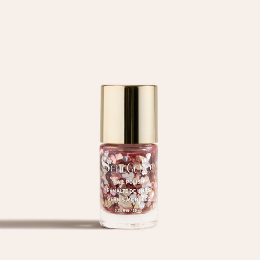 Shimmering pink glitter nail polish in a clear bottle with a gold cap